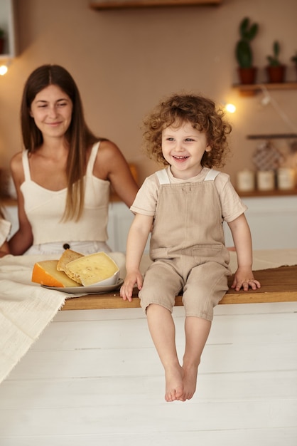 Moeder kijkt toe terwijl haar zoon aan tafel zit en kaas eet.