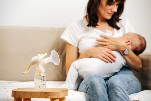 Moeder kijkt zachtjes naar de baby en geeft borstvoeding, naast de tafel staat een borstkolf voor moedermelk.