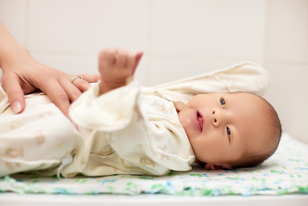 Moeder kleedt haar schattige uitgehouwen babydochter aan