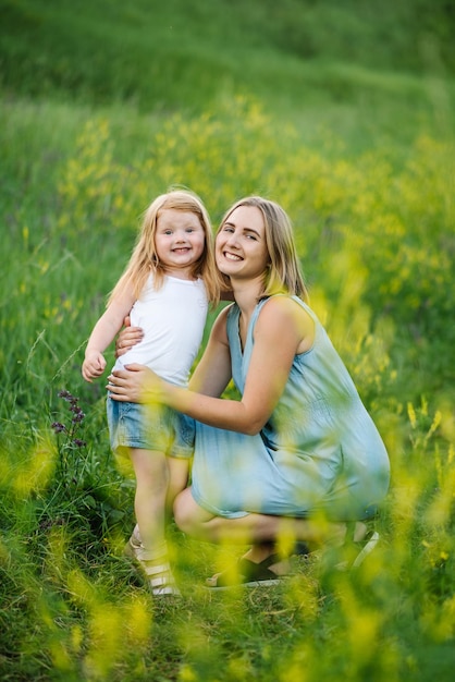 Moeder knuffelt dochter in het veld buiten Het concept van de zomervakantie Moederdag baby's dag Samen tijd doorbrengen in het park Gezinslook Zonlicht