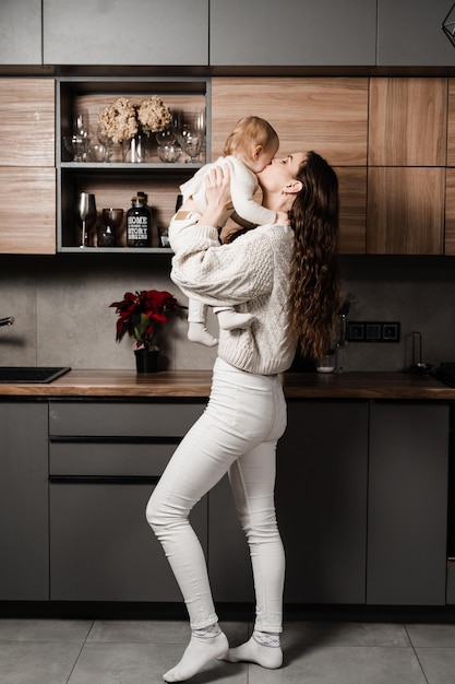 Moeder knuffelt en kust haar dochtertje in de keuken Mon en haar kind brengen samen tijd thuis door