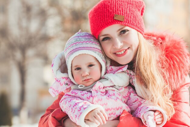 Moeder knuffelt haar dochter tijdens het wandelen op een zonnige winterdag