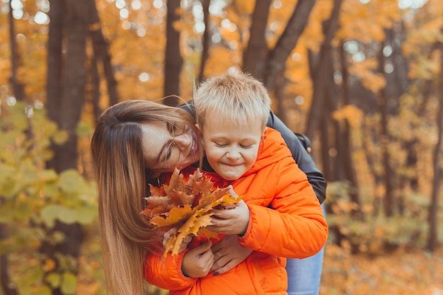 Moeder knuffelt haar kind tijdens wandeling in herfstpark herfstseizoen en alleenstaande ouder concept