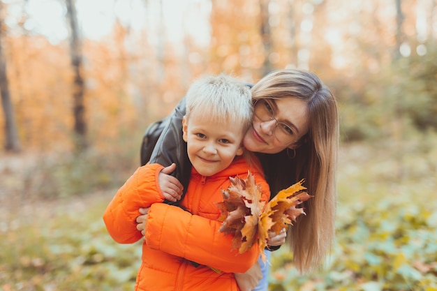 Moeder knuffelt haar kind tijdens wandeling in herfstpark herfstseizoen en alleenstaande ouder concept