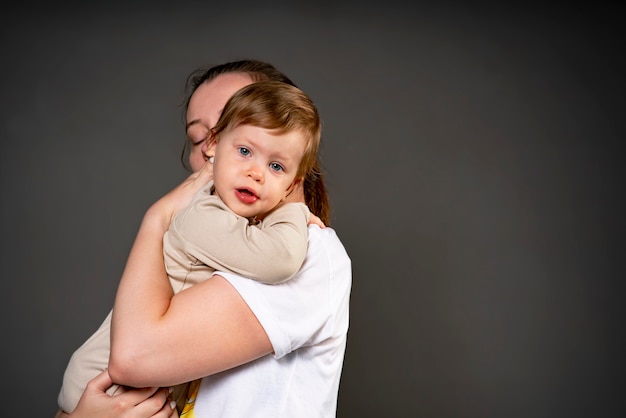 Moeder knuffelt zachtjes haar kind in de studio klein meisje in de armen van de familie van haar ouders