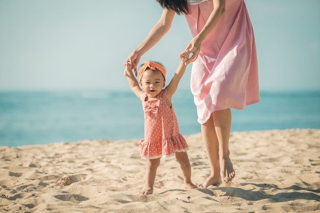 Moeder leert haar dochter wandelingen op het strand