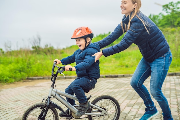 Moeder leert zoon fietsen in het park.