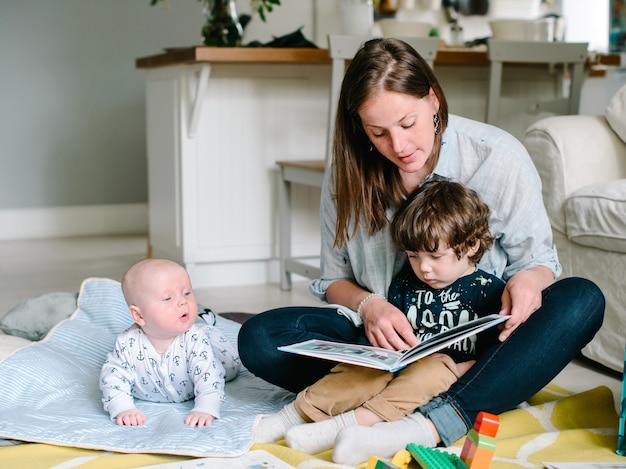 Moeder leesboek met kinderen zittend op de vloer