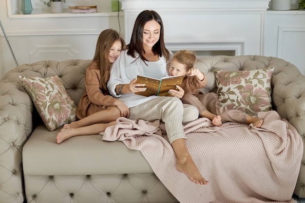 Moeder leest de kinderen een boek voor. Een vrouw vertelt een verhaal aan een jongen en een meisje voordat ze naar bed gaan. Moeder dochter en zoon ontspannen thuis op een vrije dag