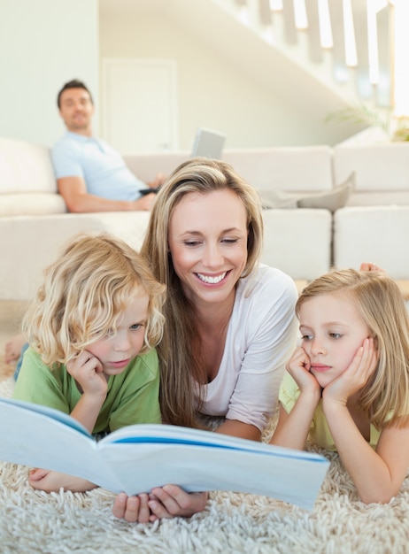 Moeder leestijdschrift met haar kinderen op de vloer