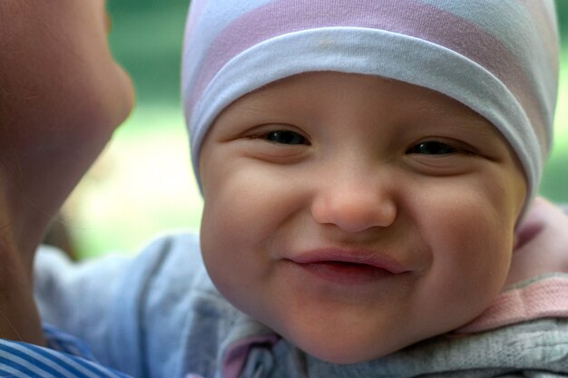 Moeder loopt met de baby in het park. Het kind in zijn armen close-up. De lente.