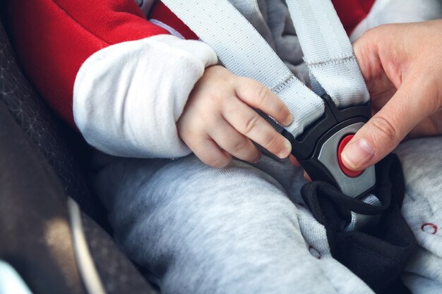 Moeder maakt een veiligheidsgordel vast in het autostoeltje waarin haar kleine kind zit