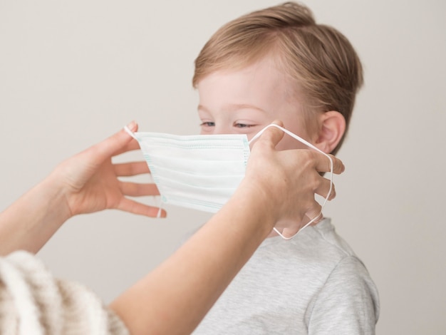 Foto moeder masker op jongen zetten