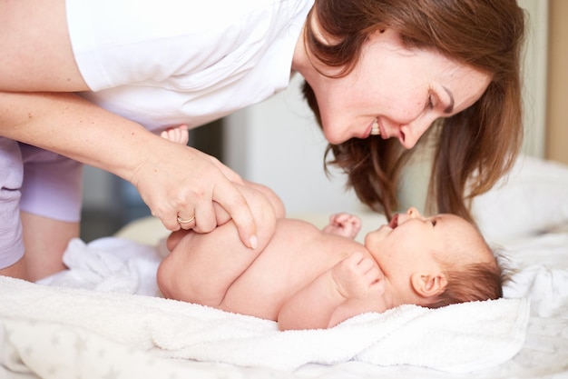 Moeder masseert haar pasgeboren babyjongen Realistisch huisportret