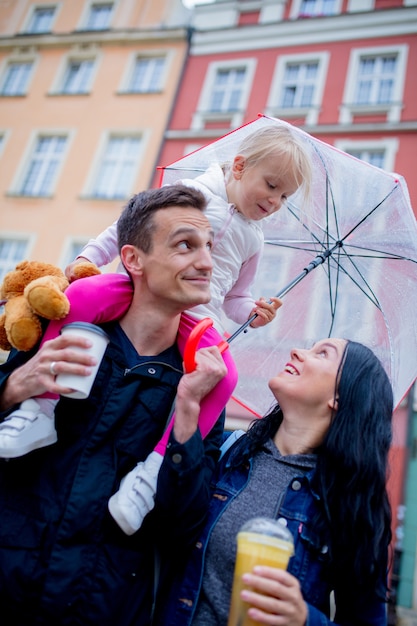 Moeder, meisje met paraplu en vader in de stad