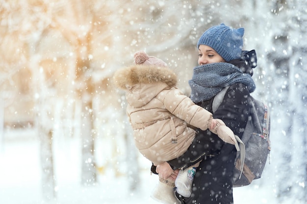 Moeder met baby op een wandeling in de winter in een sneeuwval