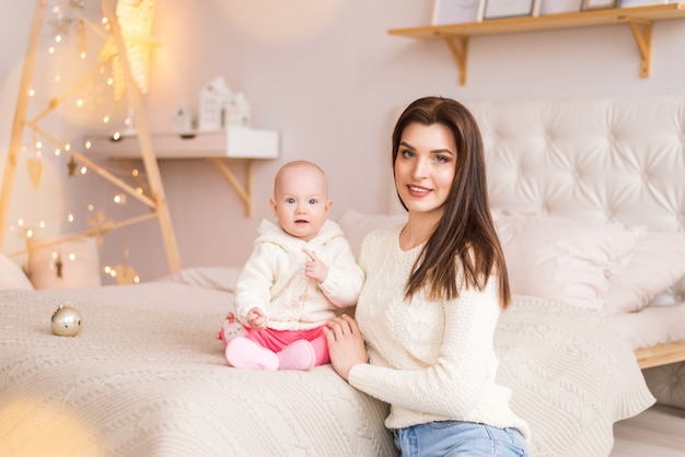 Moeder met babymeisje op de achtergrond van kerstversiering.