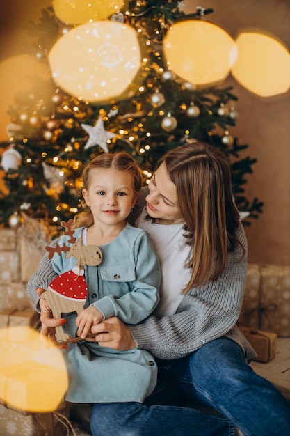 Moeder met dochter die kerstspeelgoed vasthoudt