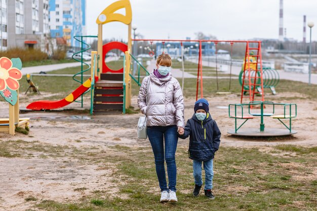 Moeder met een kind op de speelplaats, in medische maskers