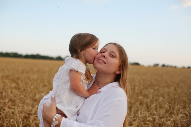 moeder met een kleine blonde dochter staan in een tederheidsfamilie in een tarweveld