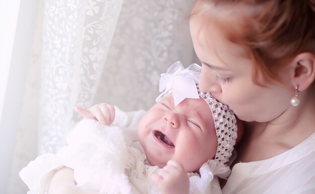 Moeder met een pasgeboren baby in haar armen. Het meisje houdt een baby voor het raam. Pasgeboren op moeder handen.