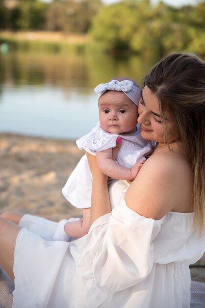 Moeder met een pasgeboren baby zit op het strand op het zand Moeder houdt een pasgeboren baby in haar armen