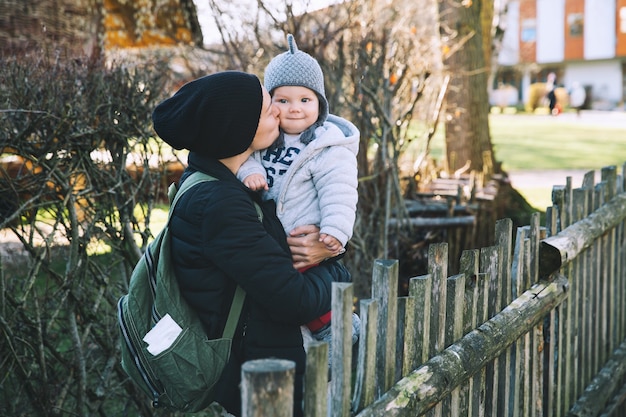 Moeder met haar baby gekleed in warme kleren die op een zonnige dag in de buitenlucht lopen