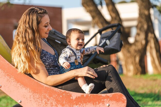 Moeder met haar baby op een glijbaan terwijl de zon ondergaat