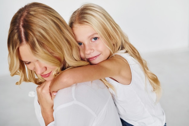 Moeder met haar dochter veel plezier samen in de studio met witte achtergrond.