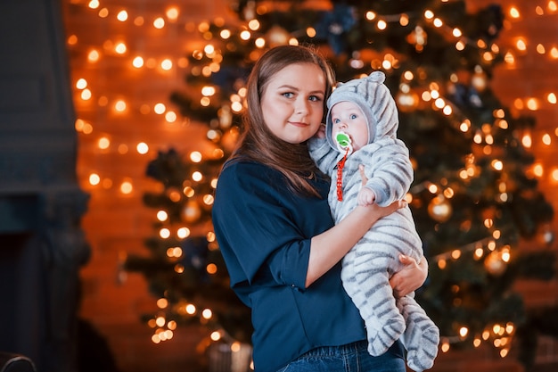 Moeder met haar kind samen in kerst ingerichte kamer.