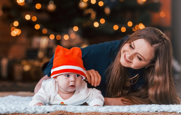 Moeder met haar kind samen in kerst ingerichte kamer.