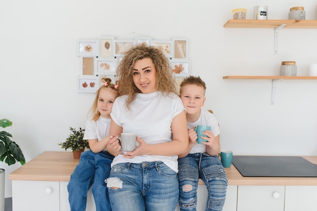 Moeder met haar twee kinderen zittend op de keukentafel.