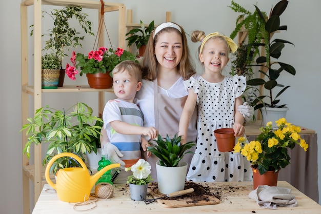 Moeder met haar zoon en dochter in nuchtere plant of transplantatie van kamerbloemen