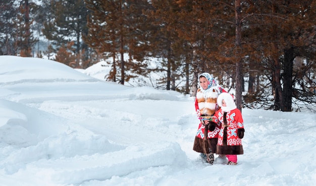 Foto moeder met kind komt uit het bos op sneeuwbanken. feestdag van de rendieren noordelijke volkeren khanty en mansi.