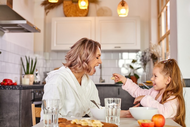 Moeder met kind meisje smakelijke havermoutpap eten voor het ontbijt