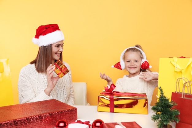 Moeder met kind zit aan het bureau met cadeautjes en kleine kerstboom