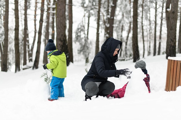 Foto moeder met kinderen die buiten spelen in het winterbos