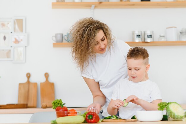 Moeder met kinderen die groentesalade thuis voorbereiden