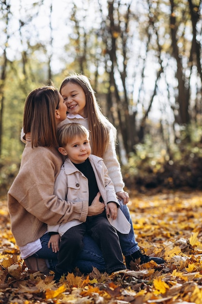 Moeder met kinderen die plezier hebben in het herfstpark