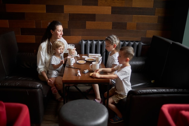 Moeder met kinderen die warme chocolademelk en latte drinken in een plaatselijke coffeeshop. Ze glimlachen en hebben plezier. moederschap concept