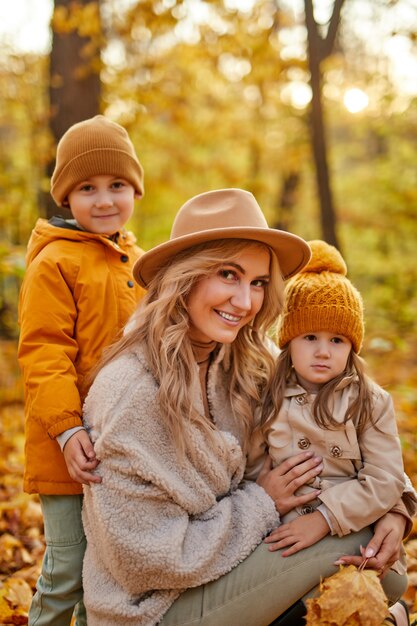 Moeder met kinderen in de herfst natuur, schattige mooie vrouw in jas genieten van tijd met kleine kinderen in de herfst bos