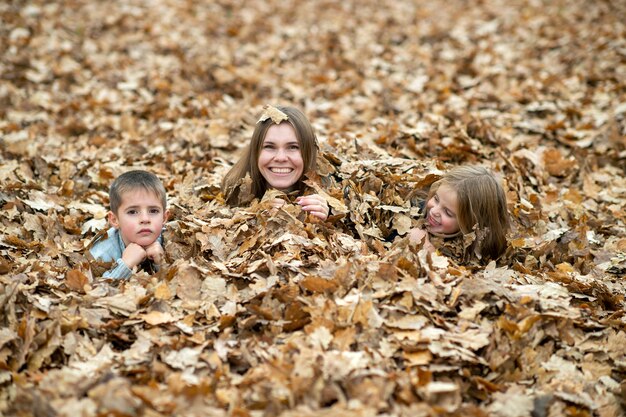 Moeder met kinderen poseren in de herfstbladeren