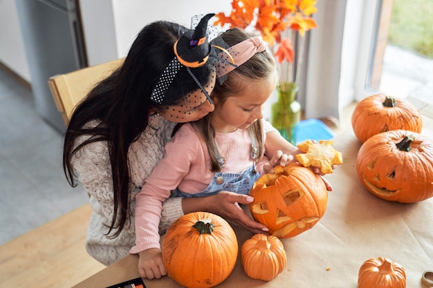 Moeder met klein meisje die pompoenen maakt voor Halloween