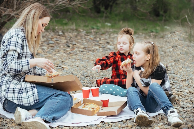 moeder met kleine dochters op een picknick in de natuur bij de rivier buiten de stad