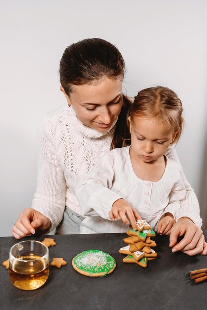 Moeder met meisje die peperkoekkoekjes versiert voor kerst