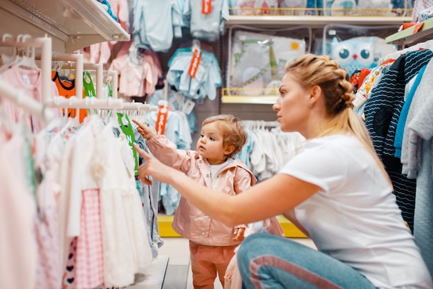 Moeder met meisje kleren kiezen in kinderwinkel