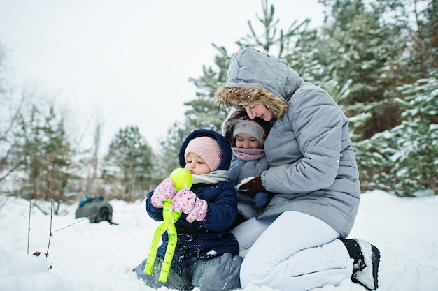 Moeder met twee dochters van babymeisjes in de winternatuur Buiten in de sneeuw