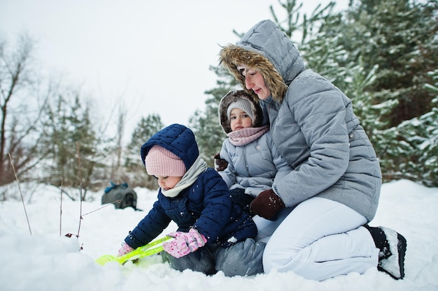 Moeder met twee dochters van het babymeisje in de winteraard. Buiten in de sneeuw.