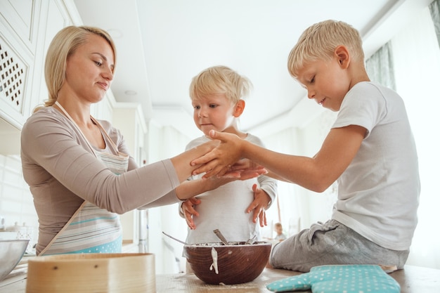 Moeder met twee zonen die vakantietaart in de keuken koken. Casual leven