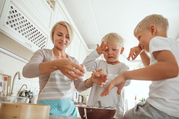 Moeder met twee zonen die vakantietaart in de keuken koken. Casual leven